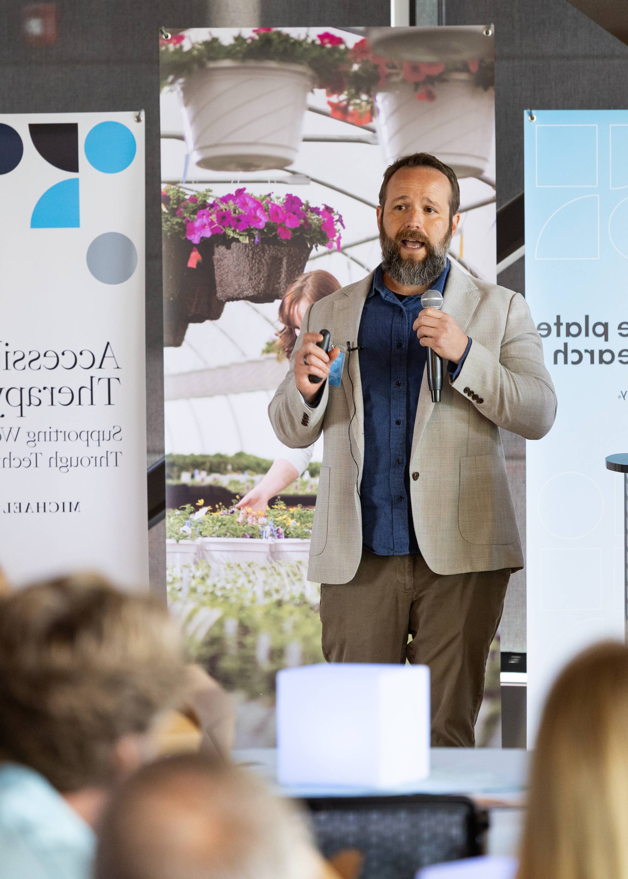 A man presenting on a stage at a Blue Plate Research Event