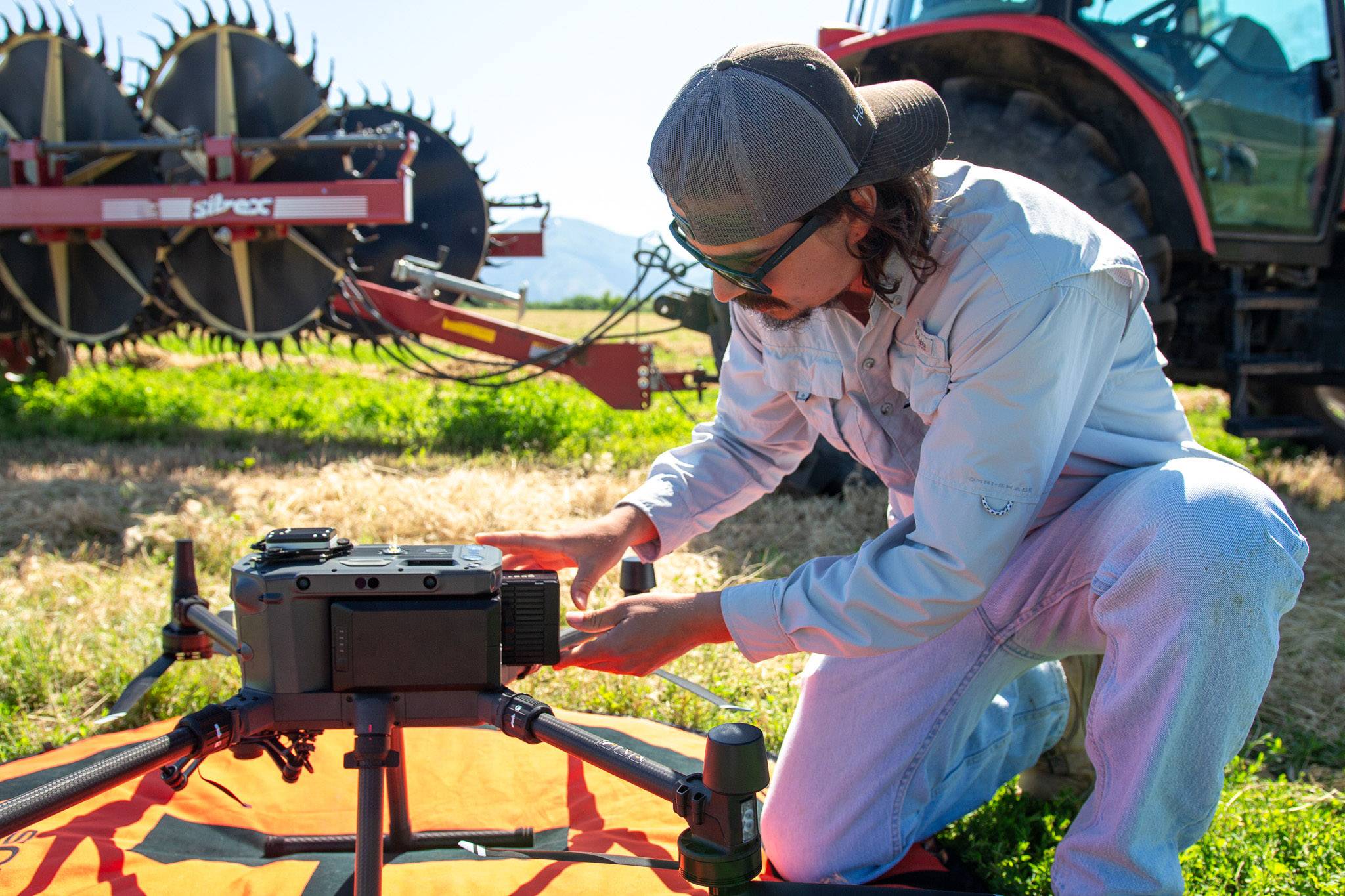 technician setting up a drone for flight over an agricultural field