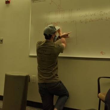 Wesley Mills in front of a white board