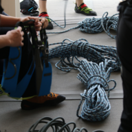 climber surrounded by climbing rope removing a harness